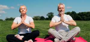 Two people in a park doing a yoga pose and practising mind and body techniques for managing leg cramps