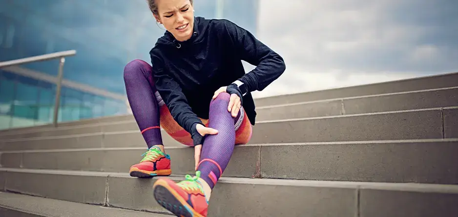 Woman on stairs clutches at her calves during in between training