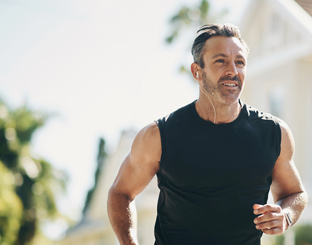 Person jogging in a sunny outdoor setting wearing a sleeveless black athletic top.
